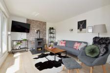 Wohnzimmer mit Couch, TV und Kamin