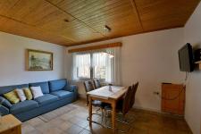 Wohnzimmer mit Couch, Esstisch und TV