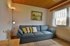 Wohnzimmer mit Couch, Esstisch und TV