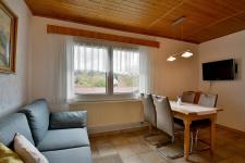 Wohnzimmer mit Couch, Esstisch und TV